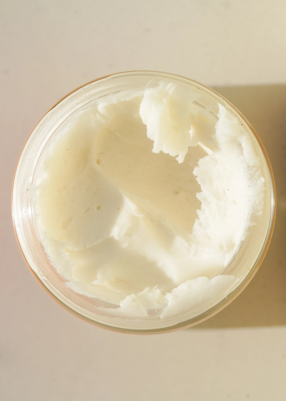Top-down close-up inside a jar of Circular Living Whipped Deodorant, showing the soft off-white whipped cream texture with scooped peaks and smooth indentations.