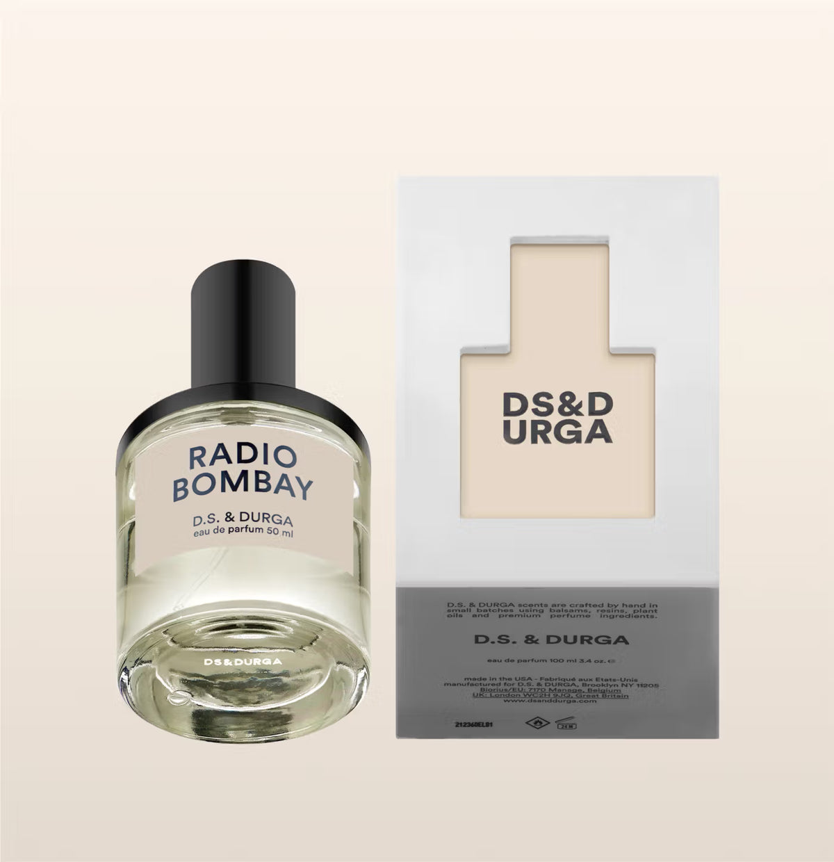D.S. & DURGA Radio Bombay eau de parfum in a clear cylindrical bottle with pale liquid, thick glass base, glossy black cap and minimalist cream label with bold dark-brown lettering.